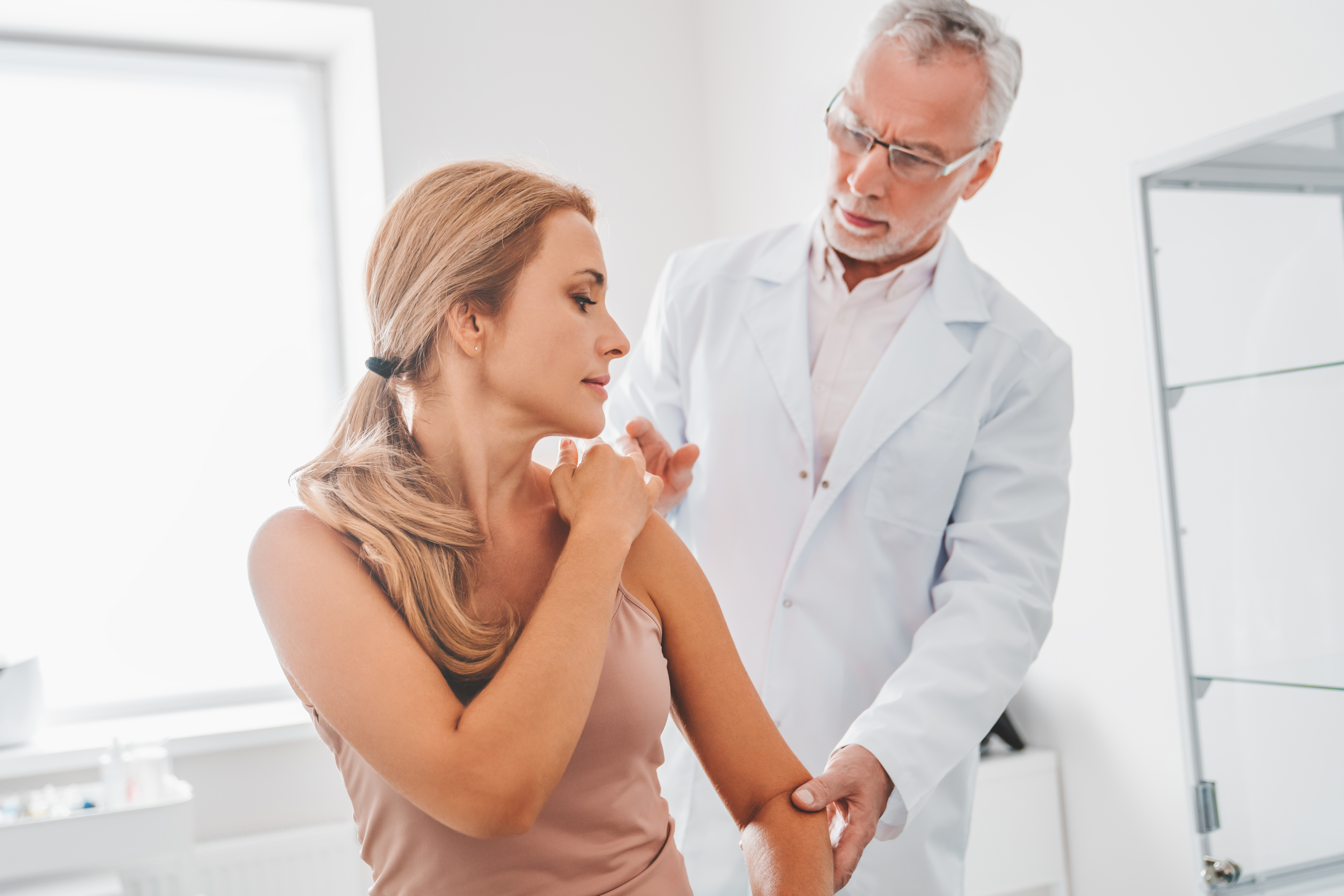woman getting shoulder checked by doctor